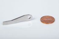 Fineblanked multitool component with ground end, next to a penny