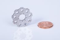 Small face plate with many holes, lapped to finish thickness, next to a penny