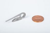 Fineblank component with semi-pierce locating pin features, next to a penny